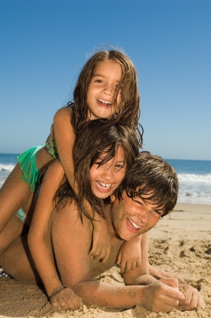 Children in swimwear playing on beachの写真素材