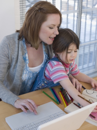 Mother Using Laptop While Daughter Colorsの写真素材