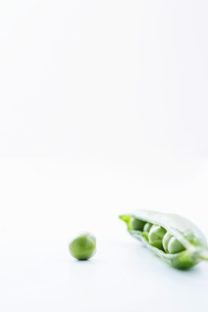 Open pea pod containing peas and single pea close-upの写真素材
