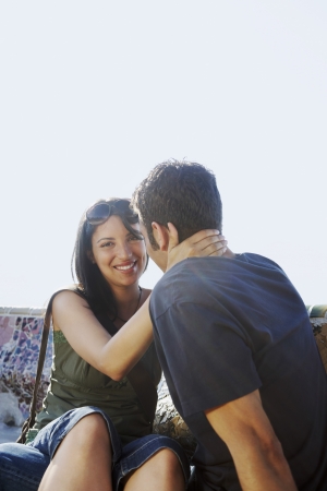 Young couple sitting on stone bench portraitの写真素材