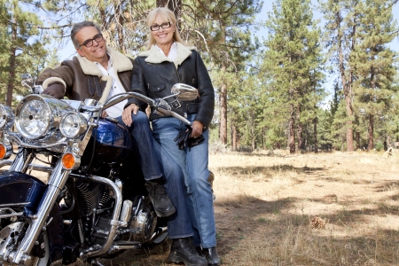 Senior couple lean on motorcycle in forestの写真素材
