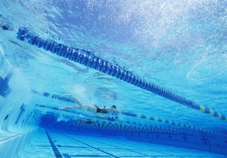 Swimmers racing together in swimming poolの写真素材