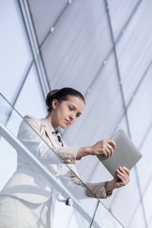 Beautiful young businesswoman using tablet computer at office railingの写真素材