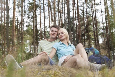 Full length of romantic young hiking couple relaxing in forestの写真素材