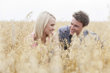 Happy man looking at woman while relaxing amidst fieldの写真素材