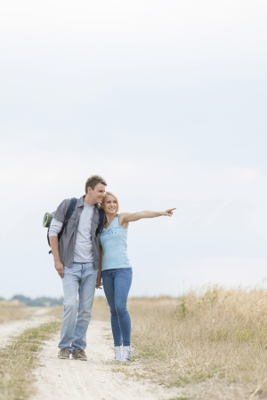 Young woman showing something to man while standing on trail at fieldの写真素材