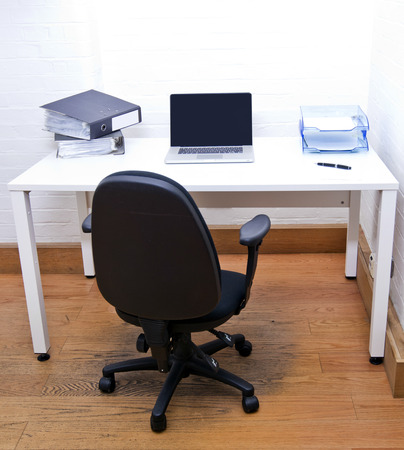 Empty office chair with laptop on deskの写真素材
