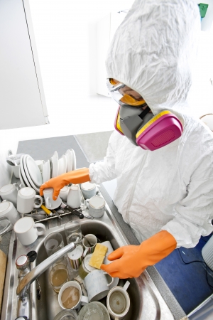 High angle view of woman in gas mask washing utensil at kitchen sinkの写真素材