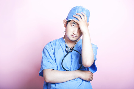 Young  Asian surgeon wearing scrubs and looking stressedの写真素材