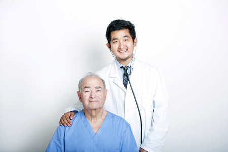 A young Asian Doctor with his hand on the shoulder of a Senior adult patientの写真素材