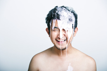 Shirtless young man with pink paint falling on his head against gray backgroundの写真素材