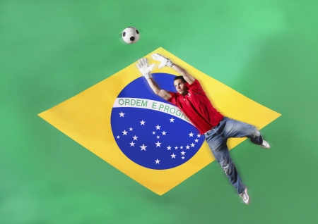 Goalkeeper saving ball in front of Brazilian flagの写真素材
