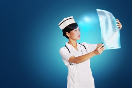 Female doctor analyzing x-ray report over blue backgroundの写真素材