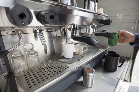 Close-up of coffee machine with hand holding cupの写真素材