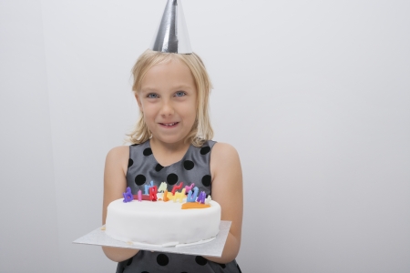 Portrait of happy girl holding birthday cake at homeの写真素材