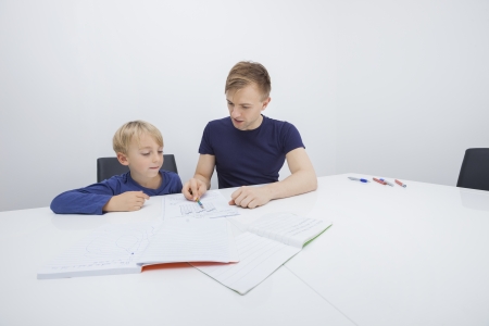 Mid adult father assisting boy in studiesの写真素材