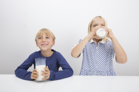 Little children drinking milk at tableの写真素材