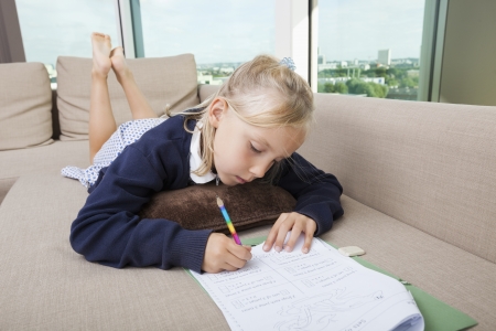 Little girl doing mathematics homework on sofaの写真素材