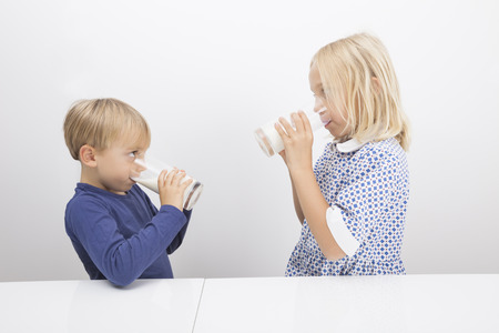 Children drinking milk while looking at each otherの写真素材