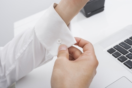 Cropped image of businessman buttoning his cuff in office