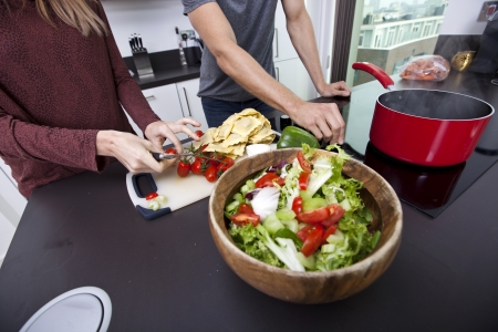 Midsection of couple cooking together at kitchen counter