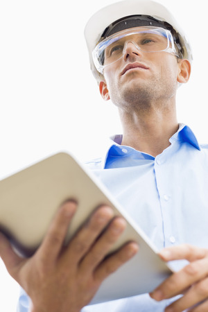 Low angle view of male architect holding tablet PC against skyの写真素材