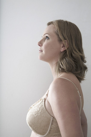 Woman in bra looking away over gray backgroundの写真素材