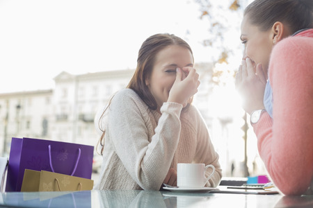 Happy women gossiping at outdoor cafe