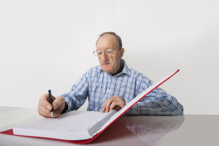 Senior businessman writing in file at deskの写真素材