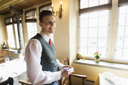 Side view of waiter with notepad smiling in restaurant