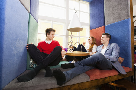 Full length of young friends having hookah at restaurantの写真素材