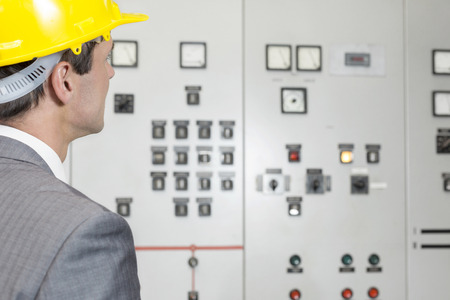 Rear view of young male supervisor examining control room in industry