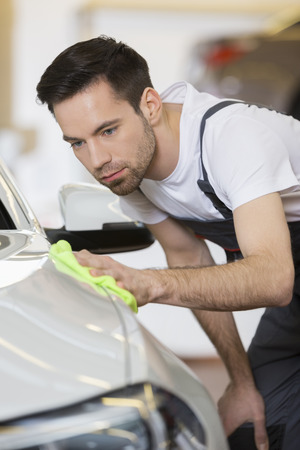 Young maintenance engineer cleaning car in repair shopの写真素材