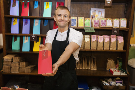 Portrait of male salesperson showing product in coffee storeの写真素材