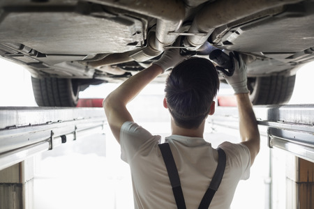Rear view of automobile mechanic examining car in workshopの写真素材