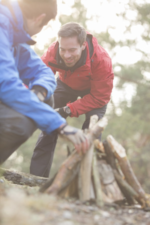 Male hikers lighting bonfire in forestの写真素材