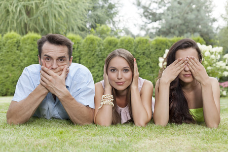 Portrait of young friends covering mouth; ears and eyes in parkの写真素材