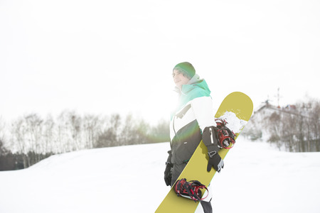 Young man with snowboard walking in snowの写真素材