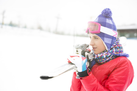 Beautiful young woman carrying skis outdoorsの写真素材