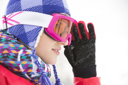 Side view close-up of beautiful young woman in ski goggles looking awayの写真素材