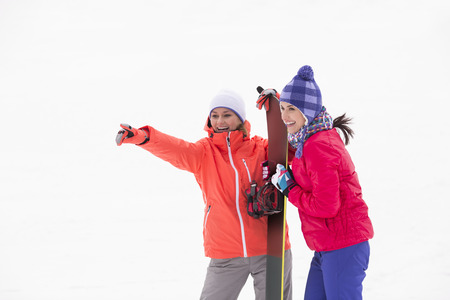 Excited female friends with snowboard outdoorsの写真素材