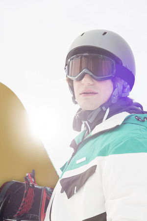 Handsome young man holding snowboard outdoorsの写真素材