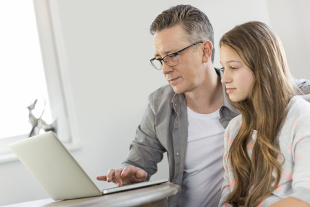 Father and daughter using laptop at homeの写真素材