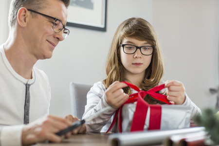 Father and daughter wrapping Christmas present at homeの写真素材