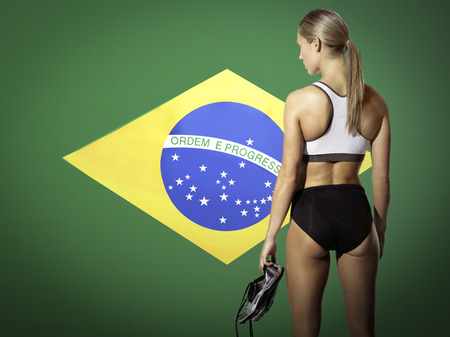 Rear view of a female athlete holding shoes against white backgroundの写真素材