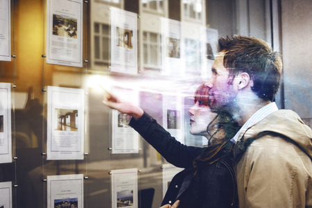 Side view of a young couple looking at window display at real estate officeの写真素材