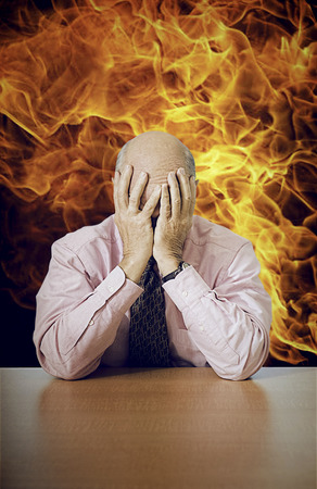 Stressed businessman with head in hands sitting at office deskの写真素材