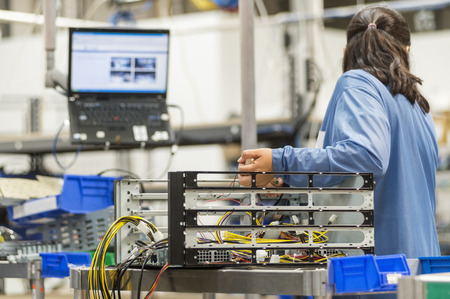 Rear view of female technician repairing computer part in electronics industryの写真素材
