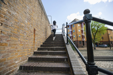 Full length rear view of young woman walking up stairs outdoorsの写真素材