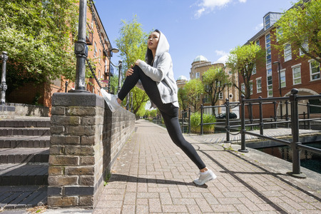 Full length side view of young fit woman stretching on sidewalkの写真素材